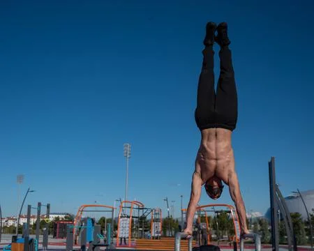 Shirtless man doing handstand on parallel bars at sports ground. Foto stock