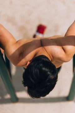 Shirtless man doing pull-ups on horizontal bar Stock-Fotos