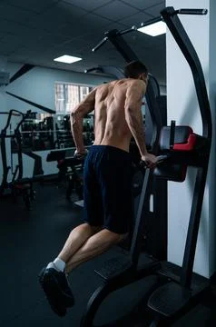 Shirtless man doing triceps dips from parallel bars in gym. Stock Photos