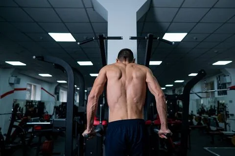 Shirtless man doing triceps dips from parallel bars in gym. Foto stock