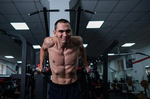 Shirtless man doing triceps dips from parallel bars in gym. 写真素材