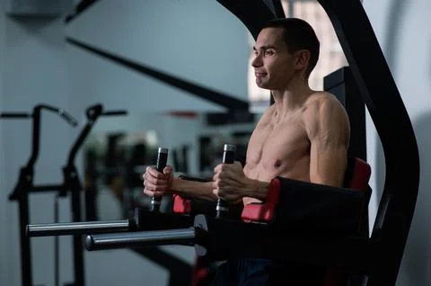 Shirtless man doing triceps dips from parallel bars in gym. Foto stock