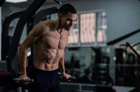 Shirtless man doing triceps dips from parallel bars in gym. Stock Photos
