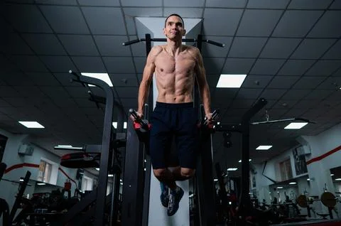 Shirtless man doing triceps dips from parallel bars in gym. Stock-Fotos