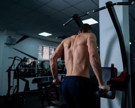 Shirtless man doing triceps dips from parallel bars in gym. Stock-Fotos