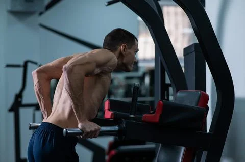 Shirtless man doing triceps dips from parallel bars in gym. Stock Photos