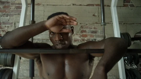 Shirtless man looking into camera while resting at the squat rack Video stock 124463722