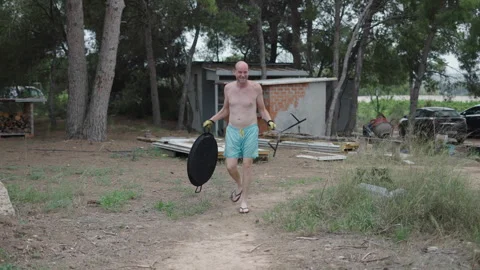 A shirtless man smiles while holding utensils to make paella Stock Footage 259958200