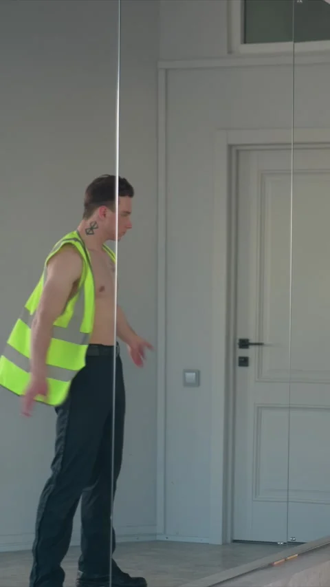 Shirtless man with tattoos putting on bright yellow high visibility safety vest Video stock 345668535
