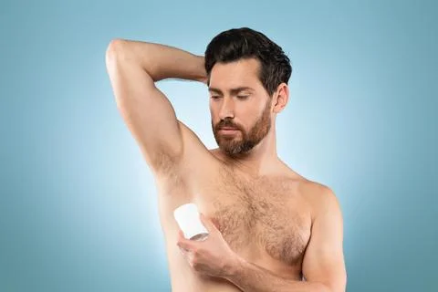 Shirtless middle aged man using deodorant on his armpit to prevent sweating Stock Photos