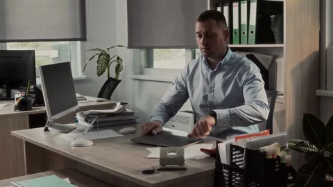 Shirtless office clerk sits down at his desk in office and opens laptop Stock-Footage 307597497