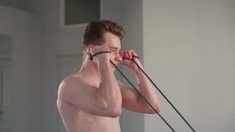 Shirtless student pulls elastic rope in hallway during resistance workout Stock Footage 308660384