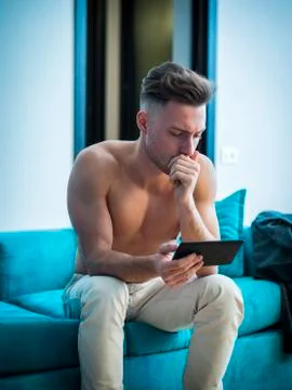 Shirtless young athletic man reading on ebook reader Stock Photos