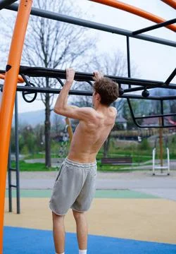 Shirtless Young Man Doing Pull-Ups on Outdoor Bar Stock Photos