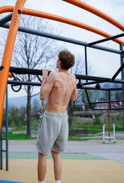Shirtless Young Man Doing Pull-Ups on Outdoor Bar Stock Photos