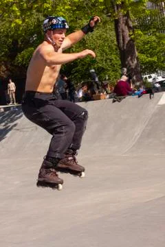 Shirtless young man jumping while running on inline roller skates at ramp Stock Photos