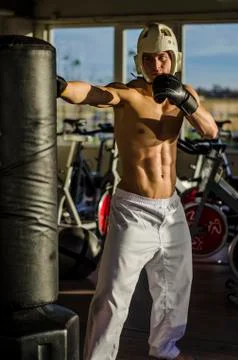 Shirtless young man using punching bag Stock Photos
