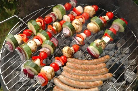 Shish-kebab and sausages cooking on barbecue Stock Photos