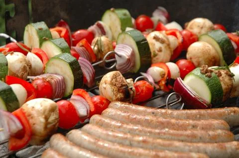 Shish-kebab and sausages cooking on barbecue Stock Photos