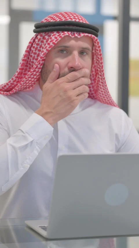 Shocked Arab Man Looking at Camera while Working on Laptop in Office, vertical Stock Footage 324777271