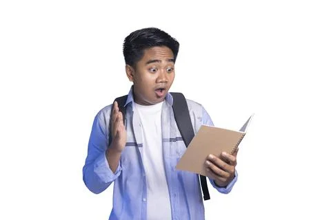 Shocked Asian student with backpack looking at an open notebook with mouth .. Stock Photos