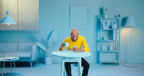 Shocked black man drinking a cup of coffee watching a shocking video or message Stock Footage 163147267