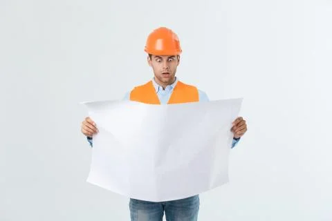 Shocked builder construction worker is holding in hand a plan draft document Stock Photos