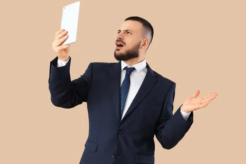 Shocked businessman using tablet computer on beige background. Search concept Stock Photos