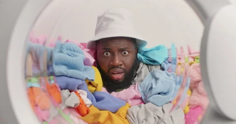 Shocked dark skinned bearded man poses around dirty laundry poses in full Stock Footage 157337795