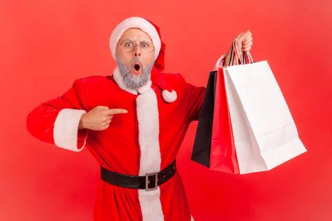 Shocked elderly man with gray beard wearing santa claus costume standing Foto stock
