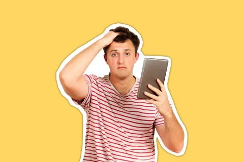 Shocked guy looking at camera and holding a tablet computer. emotional guy is Stock Photos