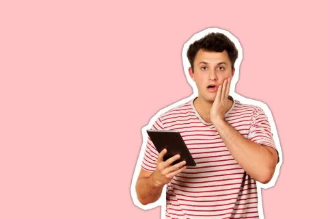 Shocked guy looking at camera and holding a tablet computer. emotional guy is Stock Photos
