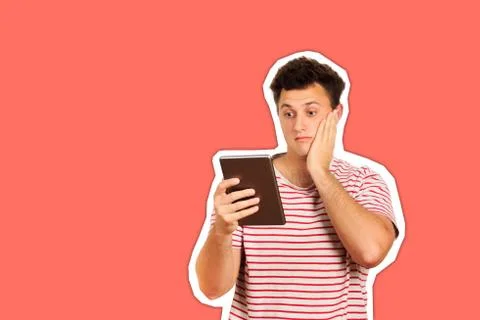 Shocked guy looking at camera and holding a tablet computer. emotional guy is Stock Photos