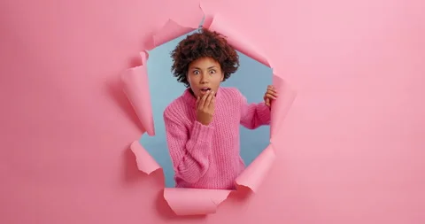 Shocked impressed dark skinned young woman looks away and points at copy space Stock Footage 143171614