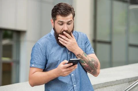 Shocked man checking up mobile phone betting results using mobile betting app in Stock Photos