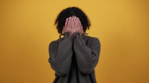 Shocked man, covers face with hands, look from fingers, isolated on yellow Stock Footage 260706113