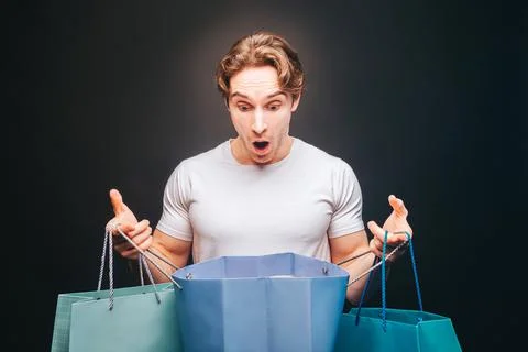 Shocked man looking in opened shopping bag Stock Photos