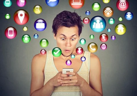 Shocked man using smartphone application icons flying out of cellphone Foto stock