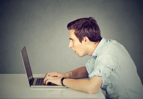 Shocked perplexed man sitting in front of laptop computer looking at screen Stock Photos