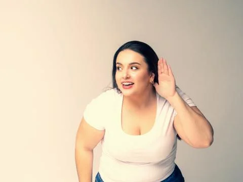 Shocked Plus Size Model with long hair posing in studio. Listen Stock Photos