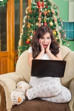Shocked woman with laptop computer sitting on armchair Stock Photos