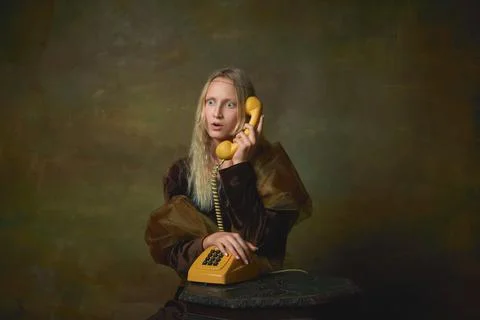Shocked young girl as Mona Lisa picture talking on retro phone over dark vintage Stock Photos