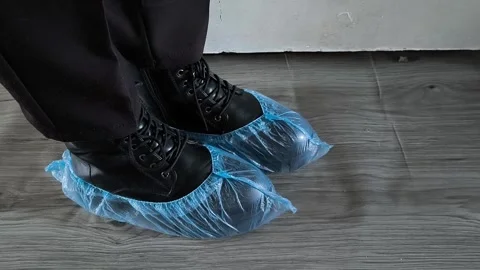 Shoe covers are worn on black shoes on womens feet. Disposable Medical Blue Shoe Video stock 320523337