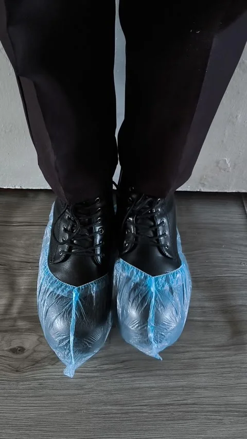 Shoe covers are worn on black shoes on womens feet. Disposable Medical Blue Shoe Stock Footage 320523352
