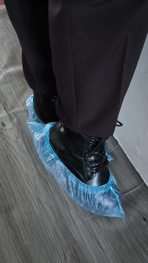 Shoe covers are worn on black shoes on womens feet. Disposable Medical Blue Shoe Stock Footage 320523374