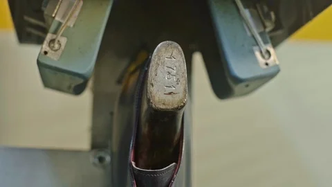 Shoe factory worker puts backside of a shoe to an industrial press machine Stock Footage 123414375
