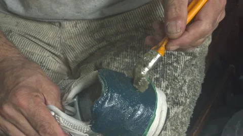 Shoe Repairman Fixes Torn Back of Sneakers by Gluing Them Stock Footage 320745526