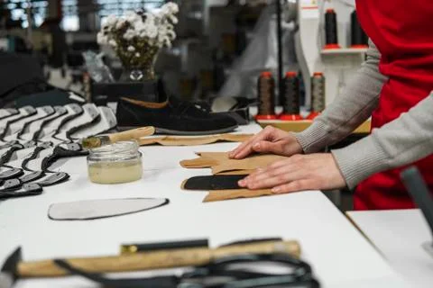 Shoemaker is adding glue with a brush to some pieces of leather that will be Stock Photos