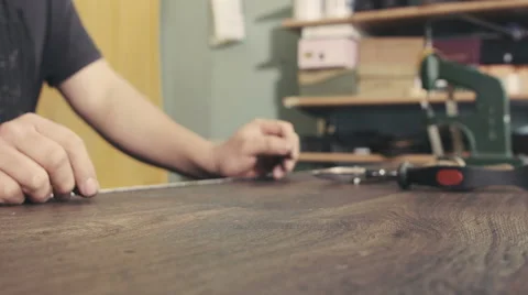 Shoemaker behind his work bench takes a pair of leather boots Vidéo 61774143