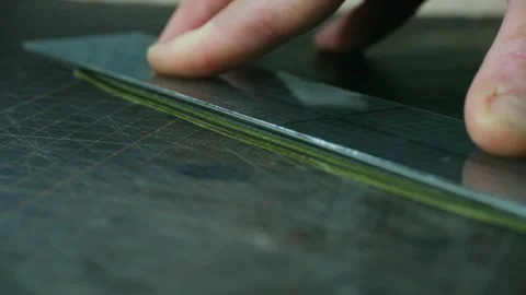 Shoemaker cutting a strip of leather with a cutter and a metal ruler Stock Footage 296552075
